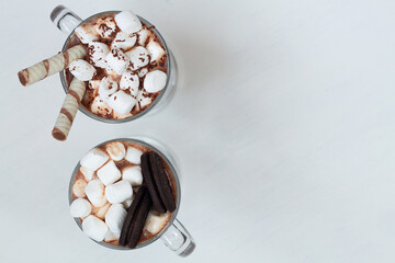 two glasses of Hot chocolate with marshmallow, cookies and wafer sticks. Winter and autumn time. Christmas drink on the white background. copy space. top view