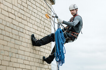 Male worker rope access industrial working at height tank oil wearing harness, helmet safety...