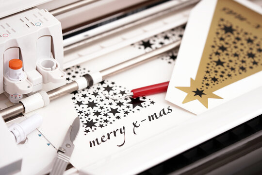 plotting machine makes large christmas stickers with star symbols and lettering from black adhesive vinyl film. DIY holiday gift and advertisement concept. selective focus. top view