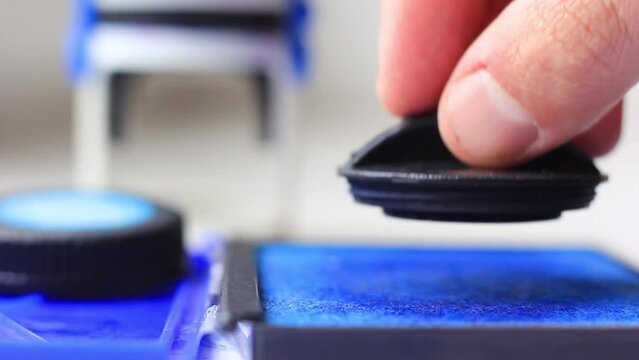 Male hand wets a stamp in ink closeup