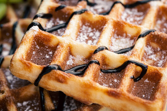Close-up, appetizing Belgian waffles drizzled with chocolate.