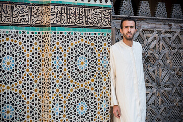 Muslim man in traditional clothing standing in front of the traditional Moroccan wall