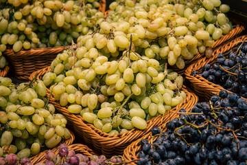 Baskets with different types of grapes on a supermarket showcase.