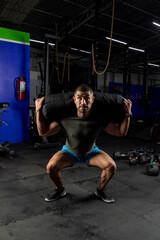 Fototapeta na wymiar man in sportswear in a gym doing squats with a sandbag on his back