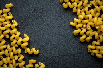 spirals of pasta on a dark background of slate stone 
