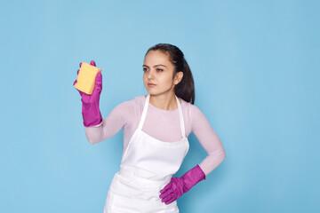 woman in gloves and cleaner apron cleaning with yellow sponge