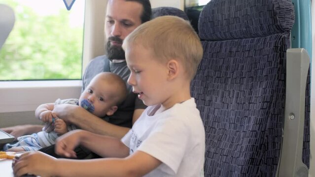 Father with two sons looking out the window at running landscapes. Traveling with Children by train. Tourism on vacation, travel around the world. Kids enjoy trip, Friendship, Transport, Fatherhood
