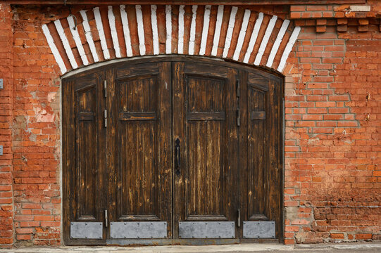an old wooden gate in a brick barn. Beautiful wooden gate