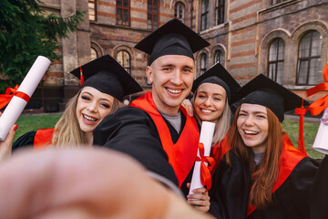 group happy graduates students use mobile phone to take selfie together. After receiving diplomas.