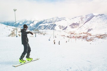 Snowboarder ride downhill on slope in Gudauri ski resort, Georgia, Caucasus mountains