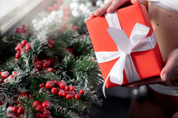 girl's hands and New Year's red gift on the background of Christmas decorations