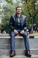 Obraz premium a young man in glasses sits on a bench