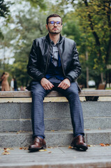 Obraz premium a young man in glasses sits on a bench