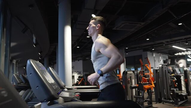 Athlete exercising on running machine in fitness gym. Fit man jogging on fitness treadmill in gym