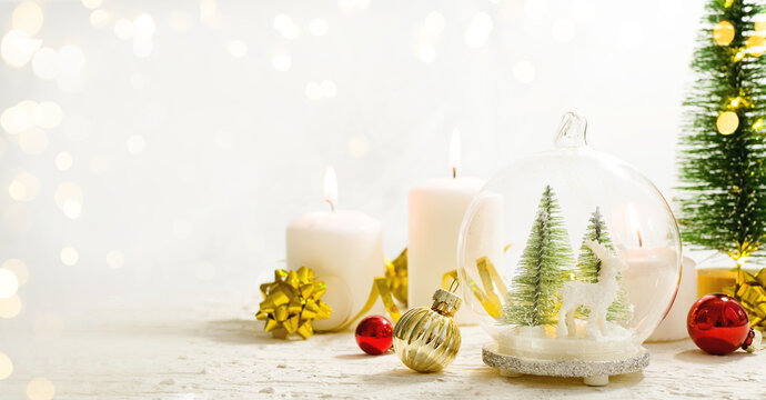 Merry Christmas. Christmas gifts, candles, surprises on white wooden table next to Christmas tree and shining lights. Advent. Greeting card or banner for website