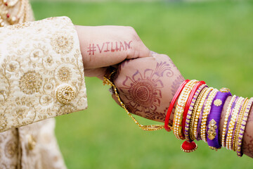 Close-up hands of bride and groom with henna drawing during traditional hindu wedding ceremony