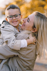 Autumn walk in the park in sunny weather. Mother and little son are walking in the park in sunny autumn weather. Beige color of clothes. Happy mother's day.