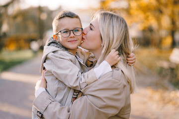 Autumn walk in the park in sunny weather. Mother and little son are walking in the park in sunny autumn weather. Beige color of clothes. Happy mother's day.