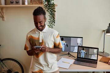Waist up portrait of creative black man as digital 3D designer using smartphone by workplace, copy...