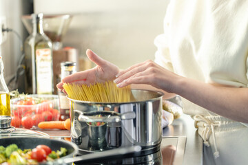 Girl cooking pasta spaghetti in pot