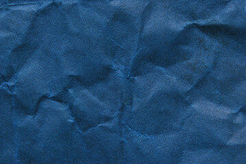 A sheet of wrinkled dark blue color paper texture as background
