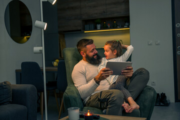 Fototapeta premium Father and daughter laughing, watching funny videos on a tablet