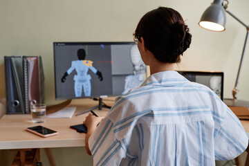 Back view of female designer building 3D models and using computer at home office workplace