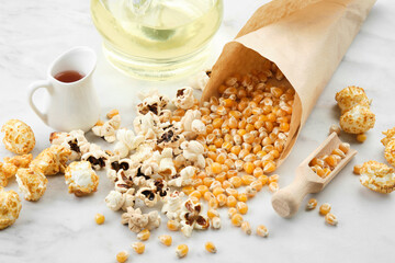 Popcorn, dried corn grains, caramel sauce and oil bottle on kitchen table.