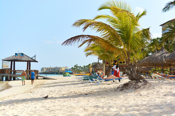 Fototapeta na wymiar A view on Palm Beach in Aruba. White sand, palms and azure Caribbean Sea. Space for copy. 