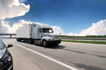 American truck with a trailer on a countryside road in motion with other car against a sky with clouds - 544198558