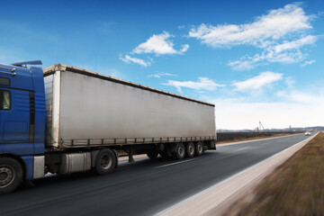 Big truck with a tailer with space for text on a road in motion against a sky with clouds - 544198586
