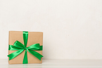 Gift box with red ribbon bow on light table