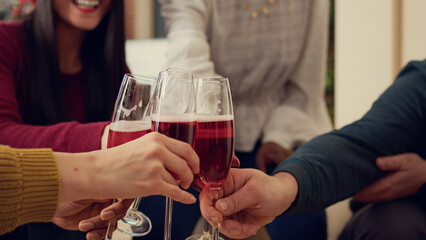 Office employees clinking glasses of wine at christmas party, celebrating winter holiday festivity with alcohol and toast. Toasting and saying cheers to celebrate xmas season with drinks. Close up.