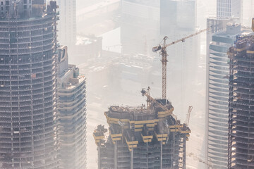 Huge skyscrappers construction site with cranes on top of buildings. Rapid urban and construction...