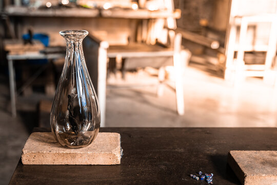 "Murano glass blowing factory. Workers put iron rod in furnace to make glass malleable.
Artist shaping hot glass into a figurine with gas flames. Artisan making glass vases and sculptures. Venice wint