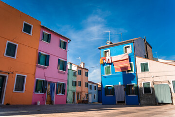 Colorful houses in Burano island near Venice Lagoon. Picturesque sunset over canal. Italy travel and landmarks. Colorful boats.