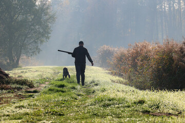 Myśliwy z psem idzie na jesienne polowanie na kaczki.  - obrazy, fototapety, plakaty