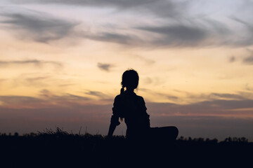 silhouette of a young girl on the background of the sunset sky