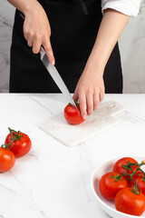 Chef slicing tomatoes on the kitchen table