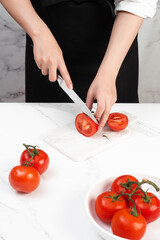 Chef slicing tomatoes on the kitchen table