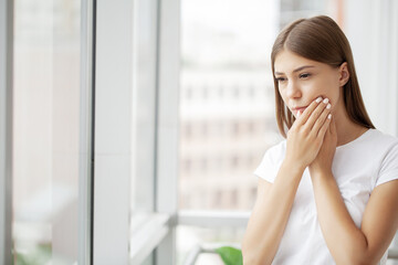 Young female business woman feels a toothache in her office