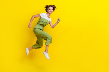 Fototapeta na wymiar Side profile photo of attractive active girl wear khaki overalls hurry running shopping center low prices summer isolated on yellow color background