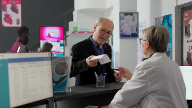 Elderly client asking pharmacist about prescription paper, wanting to buy medical treatment and box of supplements. Talking to specialist at pharmacy counter desk, medicine pills.