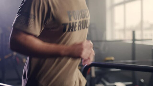 Young handsome athletic man jogging on modern digital display treadmill exercising in the gym alone. Healthy lifestyle, movement and sports