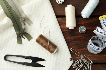 Threads and other sewing supplies on wooden table, flat lay