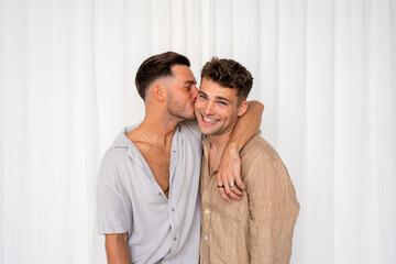 Beautiful Gay couple kiss on cheek with white curtain background