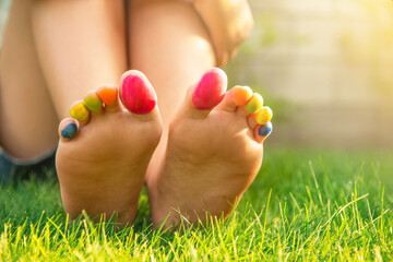 Naklejka premium Teenage girl with painted toes sitting on green grass outdoors, closeup