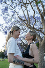 Fototapeta premium Lesbian couple hugging under beautiful tree in park 