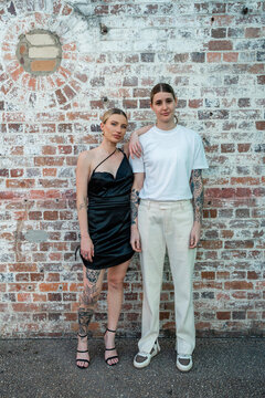 cool lesbian couple serious in front of brick wall
