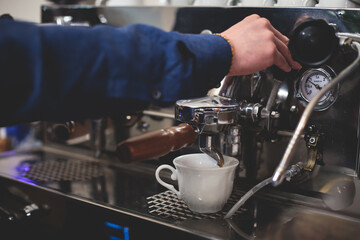 View of barista working at coffee machine in coffee house bar, bartender barman making cappuccino or latte, bartender preparing coffee drink at the cafe counter